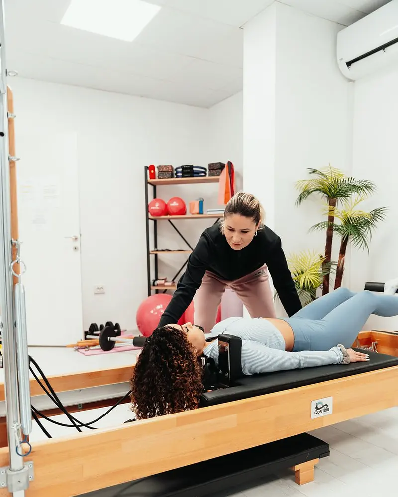 Instrutora acompanhando aluna durante exercício no reformer